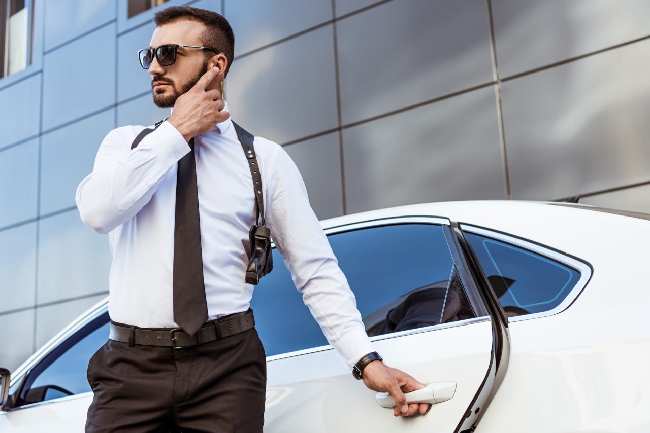 handsome-security-guard-listening-message-with-security-earpiece-on-street-and-opening-car.jpg